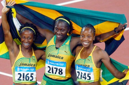 Fraser, Stewart and Simpson of Jamaica wave their national flag as they celebrate the victory of Fraser in the women's 100m final in the National Stadium at the Beijing 2008 Olympic Games